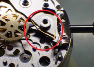 カルティエ  サントス100 丸穴車を取り外してみました。コハゼバネは丸穴車と右下・左上の先端にテンションがかかった状態で組み込まれています。